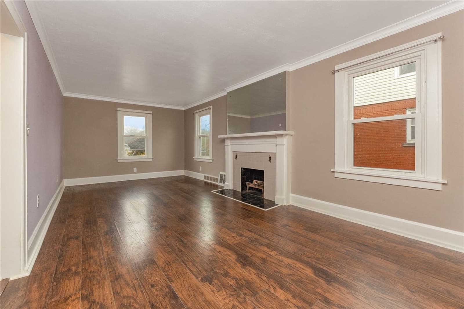 Living room with a brick fireplace and dark vinyl floors